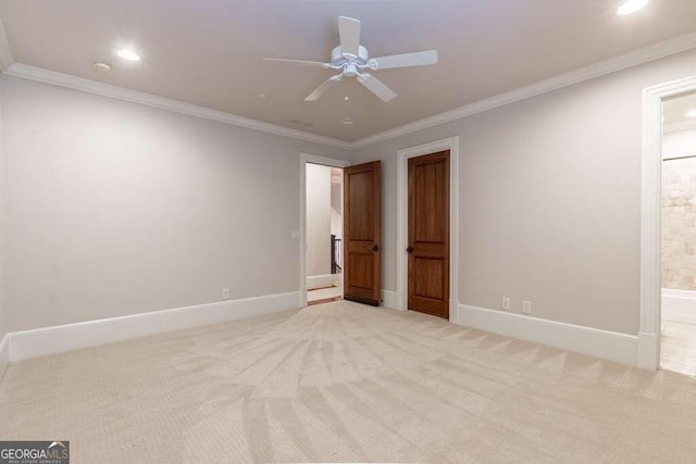 unfurnished bedroom featuring ensuite bath, ceiling fan, crown molding, and light colored carpet