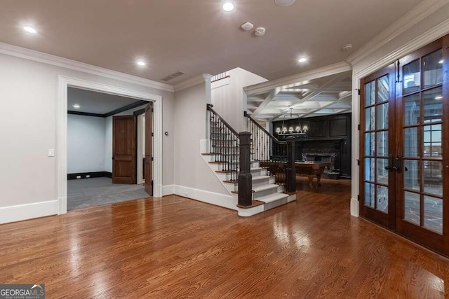 interior space with a notable chandelier, french doors, crown molding, and wood-type flooring