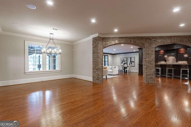 unfurnished living room featuring a notable chandelier, crown molding, and dark hardwood / wood-style flooring