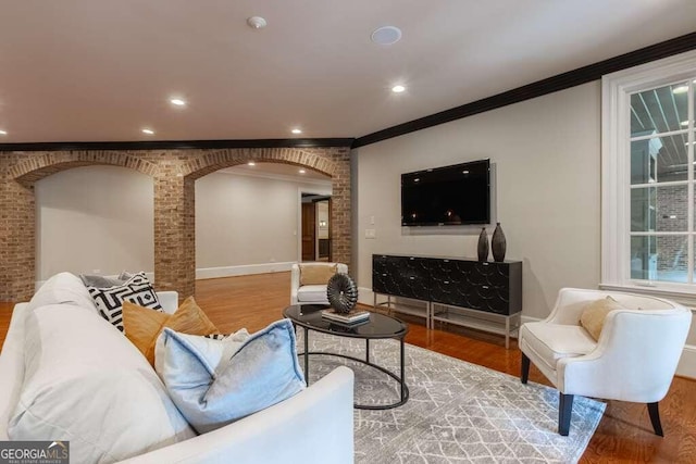 living room with brick wall, wood-type flooring, and crown molding