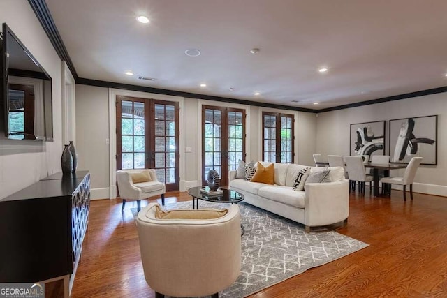 living room featuring french doors, wood-type flooring, and crown molding