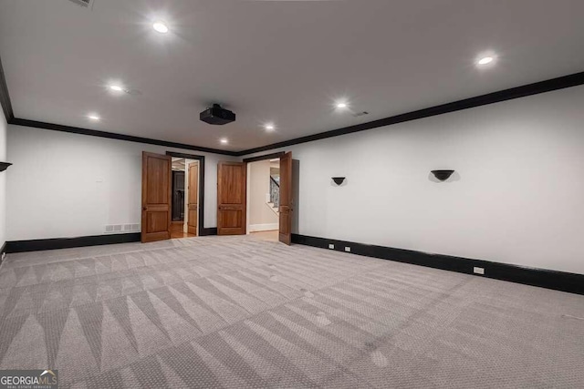 home theater room with ornamental molding and light carpet