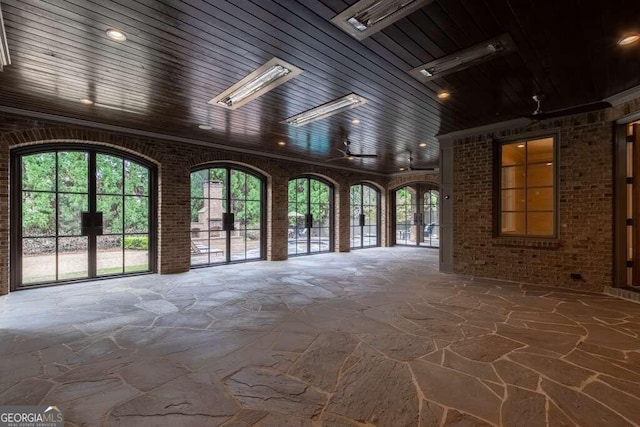 unfurnished living room featuring brick wall and ceiling fan