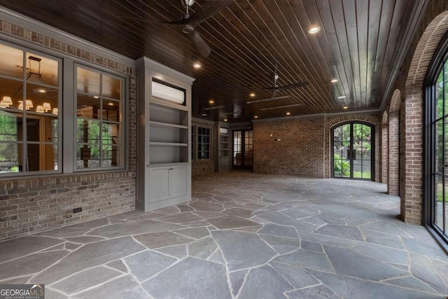 interior space featuring brick wall, ceiling fan, and wood ceiling