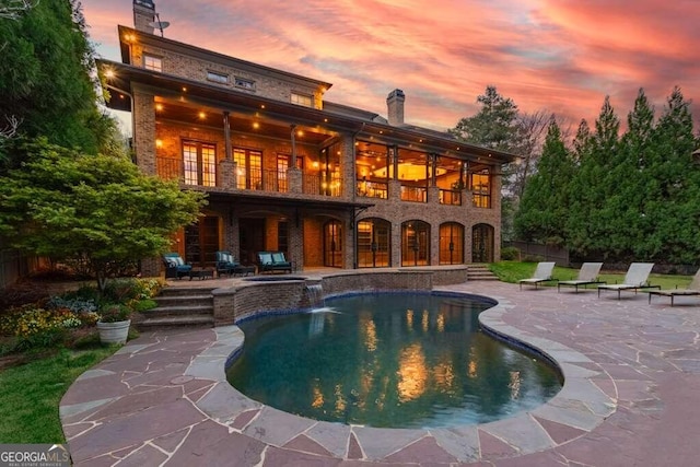 pool at dusk with a patio area