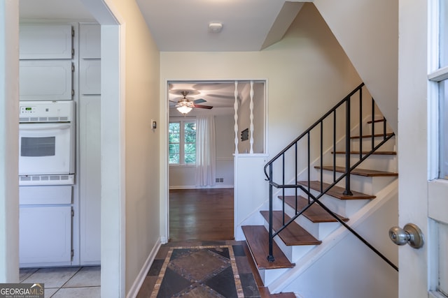 stairway with hardwood / wood-style flooring and ceiling fan