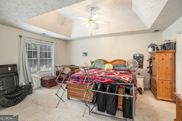 bedroom with a raised ceiling, ceiling fan, carpet, and a textured ceiling