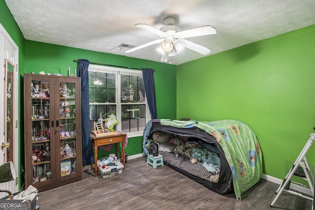 bedroom with ceiling fan, dark hardwood / wood-style floors, and a textured ceiling