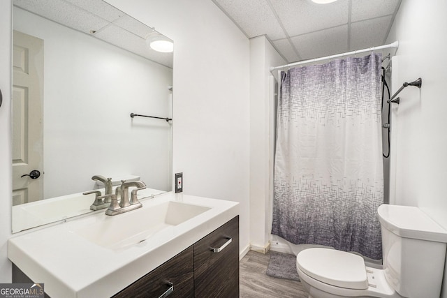 bathroom featuring a drop ceiling, vanity, a shower with curtain, toilet, and wood-type flooring