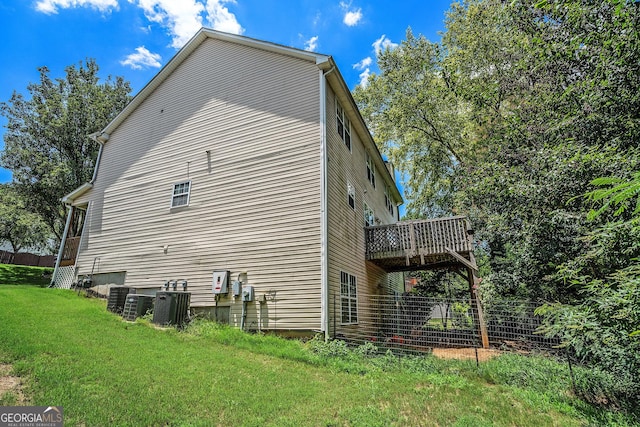 view of side of property with cooling unit, a yard, and a wooden deck