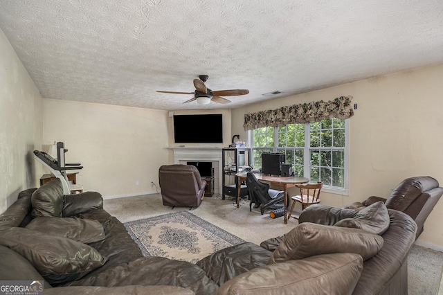 carpeted living room featuring ceiling fan and a textured ceiling