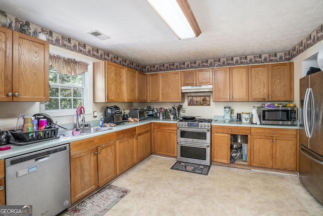 kitchen with sink, a textured ceiling, and appliances with stainless steel finishes