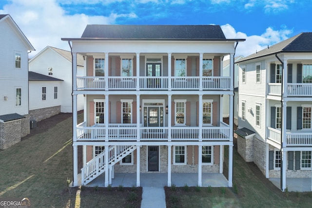 view of front facade featuring a balcony, a patio, a front yard, and central AC