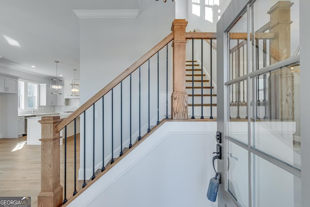 stairway featuring hardwood / wood-style floors, a notable chandelier, sink, and crown molding