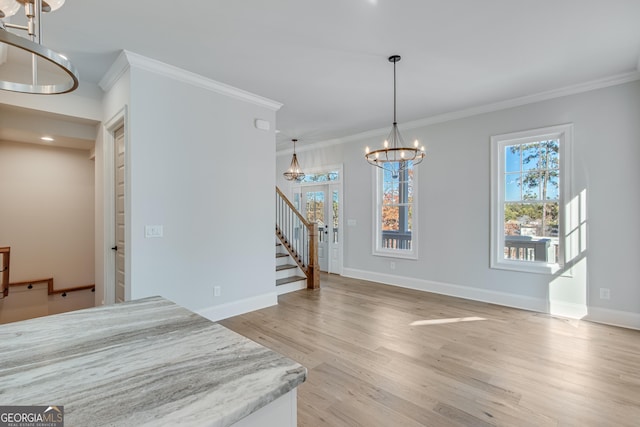 unfurnished dining area with crown molding, light hardwood / wood-style floors, and an inviting chandelier