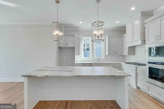 kitchen with white cabinets, appliances with stainless steel finishes, light wood-type flooring, and a kitchen island