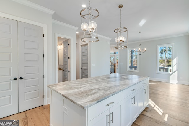 kitchen featuring crown molding, white cabinetry, hanging light fixtures, and light hardwood / wood-style flooring