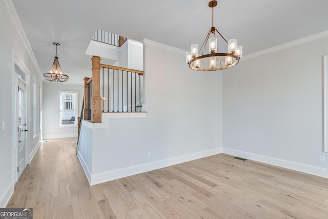 spare room featuring ornamental molding, a notable chandelier, and light wood-type flooring