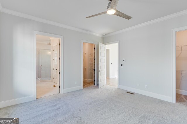 unfurnished bedroom with ceiling fan, a closet, a spacious closet, and ensuite bath