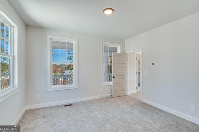 unfurnished room featuring a wealth of natural light and light carpet