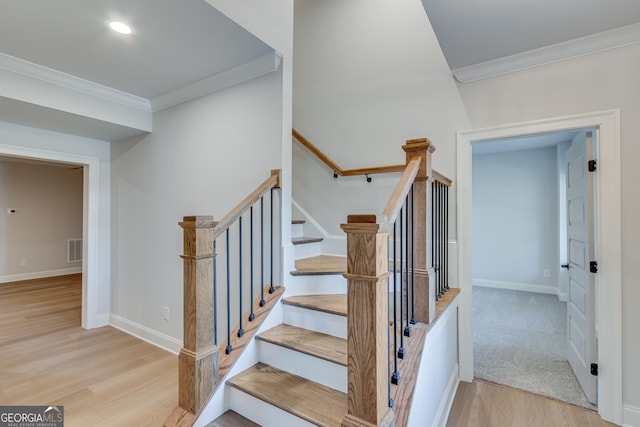 stairway with hardwood / wood-style floors and crown molding