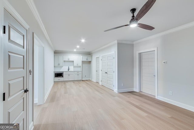 unfurnished living room with crown molding, light hardwood / wood-style flooring, ceiling fan, and sink