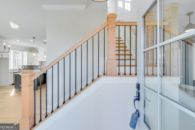 stairs featuring hardwood / wood-style floors, a notable chandelier, and ornamental molding