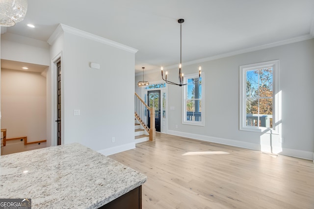 unfurnished dining area featuring light hardwood / wood-style floors, ornamental molding, and an inviting chandelier