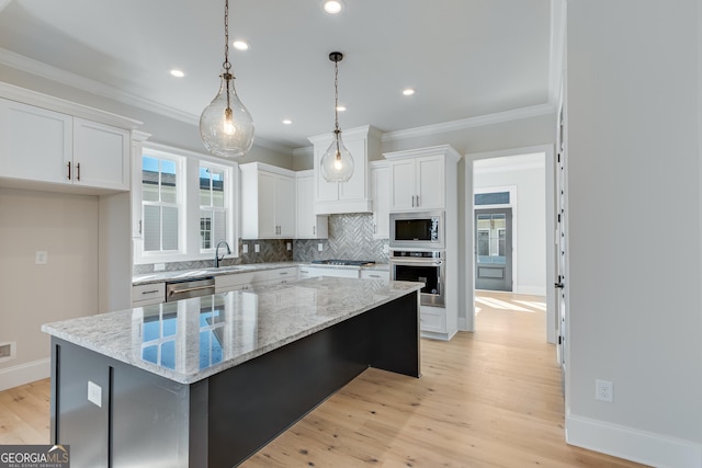 kitchen featuring a kitchen island, light stone counters, white cabinetry, and stainless steel appliances