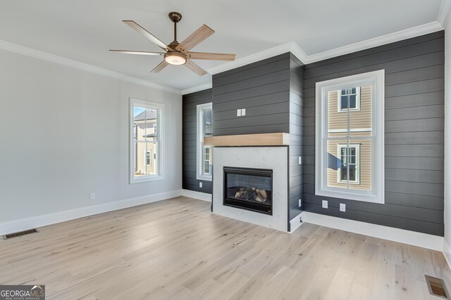 unfurnished living room with ceiling fan, a large fireplace, crown molding, and light hardwood / wood-style flooring