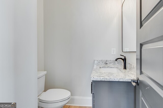 bathroom with hardwood / wood-style flooring, vanity, and toilet