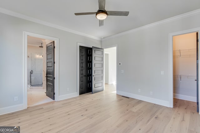 unfurnished bedroom featuring a spacious closet, ceiling fan, light wood-type flooring, and crown molding