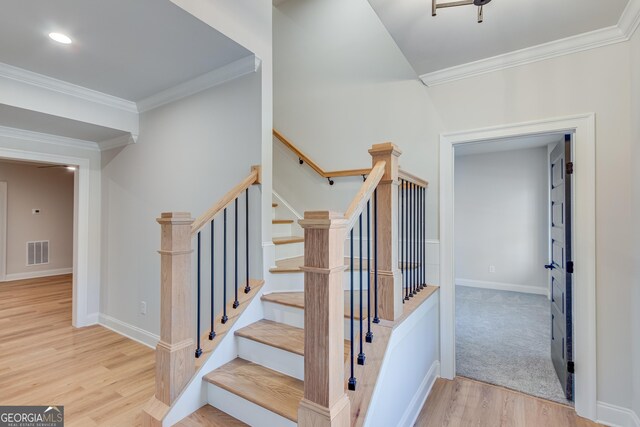 stairs with wood-type flooring and ornamental molding