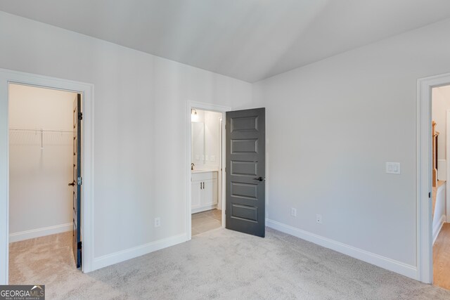 bedroom featuring light colored carpet, a spacious closet, and a closet