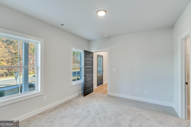 unfurnished bedroom featuring light carpet and multiple windows