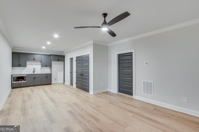 unfurnished living room featuring light hardwood / wood-style flooring, ceiling fan, ornamental molding, and sink