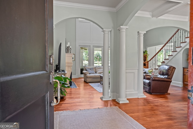 entrance foyer featuring beam ceiling, hardwood / wood-style flooring, crown molding, and ornate columns