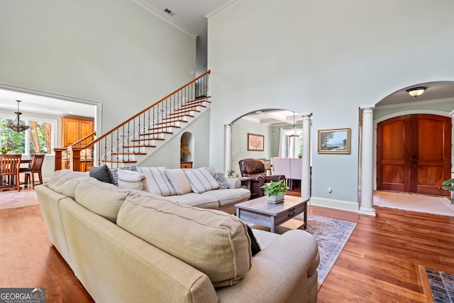 living room featuring decorative columns, a high ceiling, hardwood / wood-style flooring, and ornamental molding