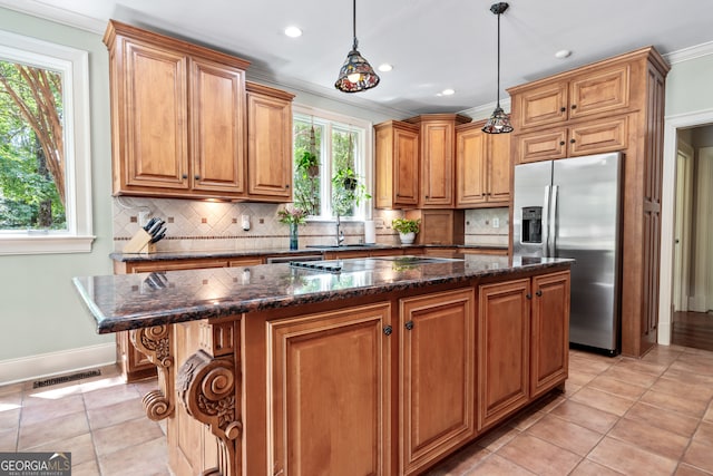 kitchen with decorative backsplash, pendant lighting, a kitchen island, stainless steel fridge, and light tile patterned floors