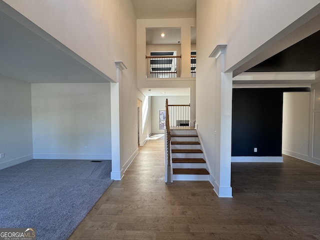 stairs featuring a high ceiling and hardwood / wood-style flooring