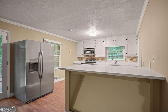 kitchen featuring white cabinets, appliances with stainless steel finishes, light hardwood / wood-style floors, sink, and backsplash