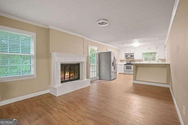 unfurnished living room with a textured ceiling, light hardwood / wood-style flooring, and crown molding