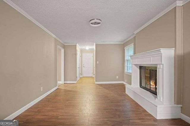 unfurnished living room featuring hardwood / wood-style floors, ornamental molding, and a textured ceiling