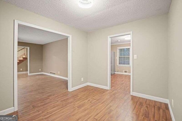 unfurnished room featuring a textured ceiling and light wood-type flooring