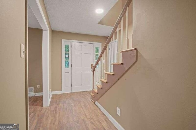 foyer entrance featuring light wood-type flooring and a textured ceiling