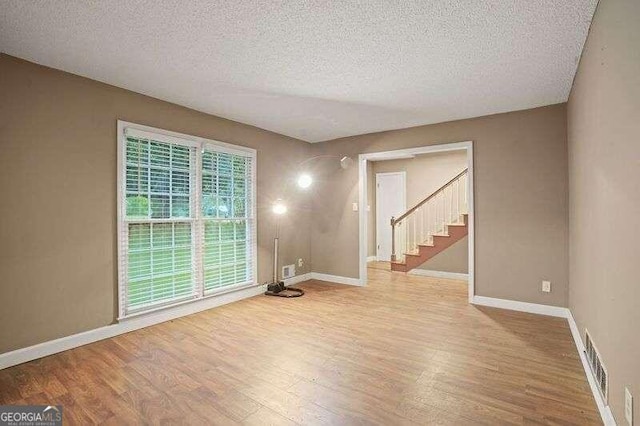 empty room with a textured ceiling and light hardwood / wood-style floors