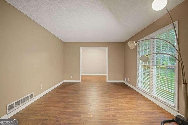 unfurnished room with a textured ceiling and light hardwood / wood-style floors