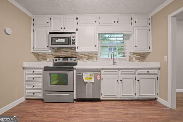 kitchen with white cabinets, sink, stainless steel appliances, and a textured ceiling