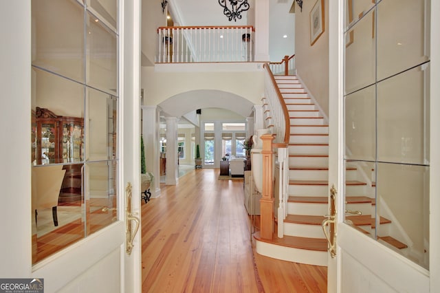 entrance foyer featuring decorative columns, light hardwood / wood-style flooring, and a towering ceiling