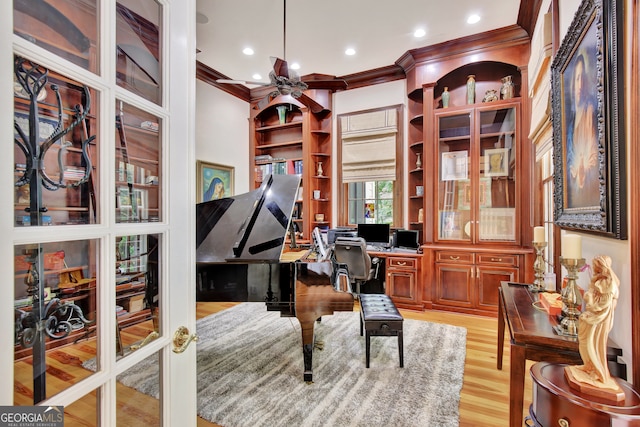 home office featuring built in desk, crown molding, light hardwood / wood-style flooring, and ceiling fan